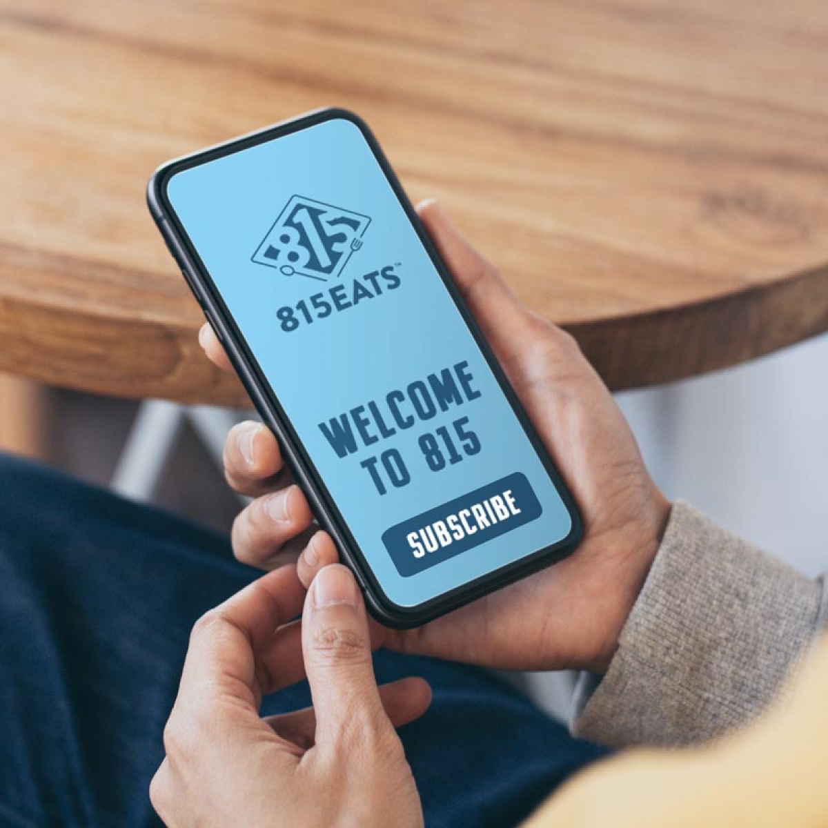Woman holding a phone with a subscribe button and says Welcome to 815